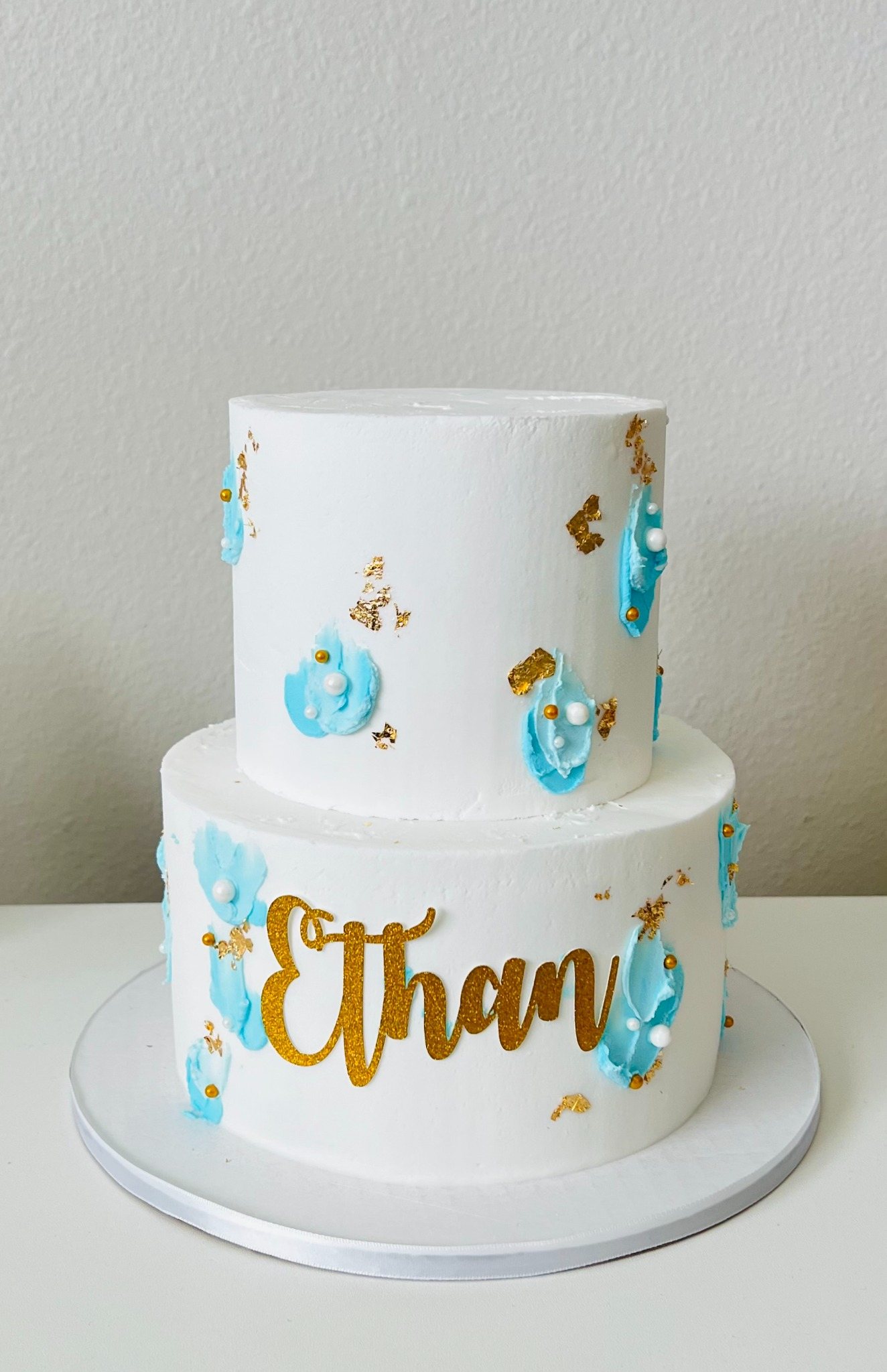 White two tier cake with aqua and gold accents