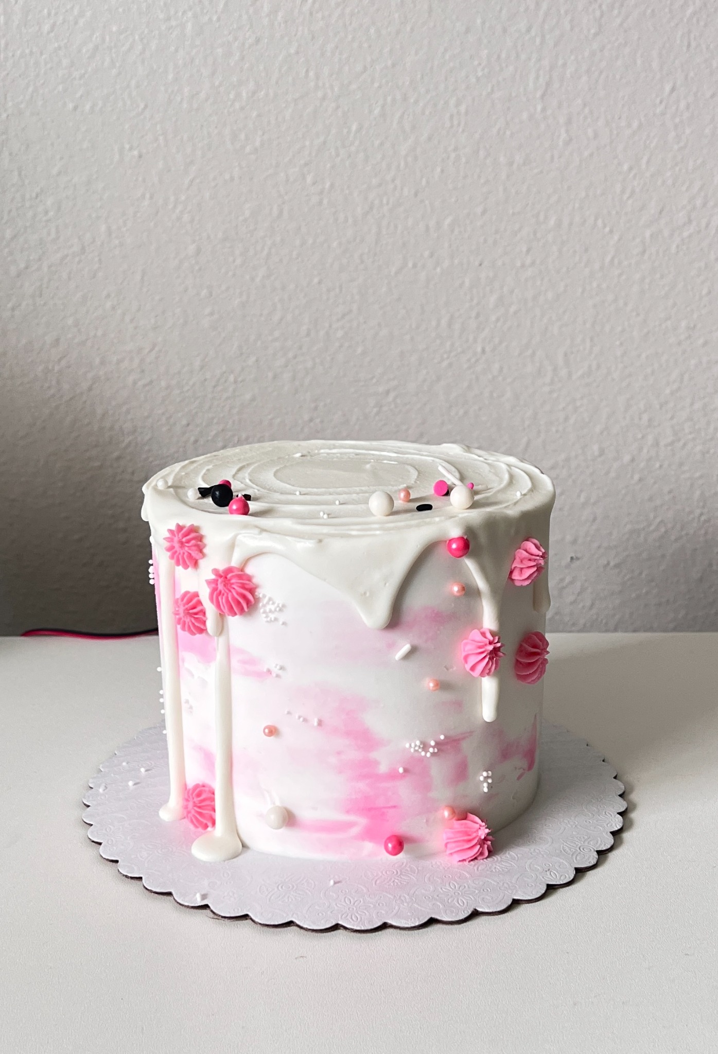 Pink and white drip cake with floral accents