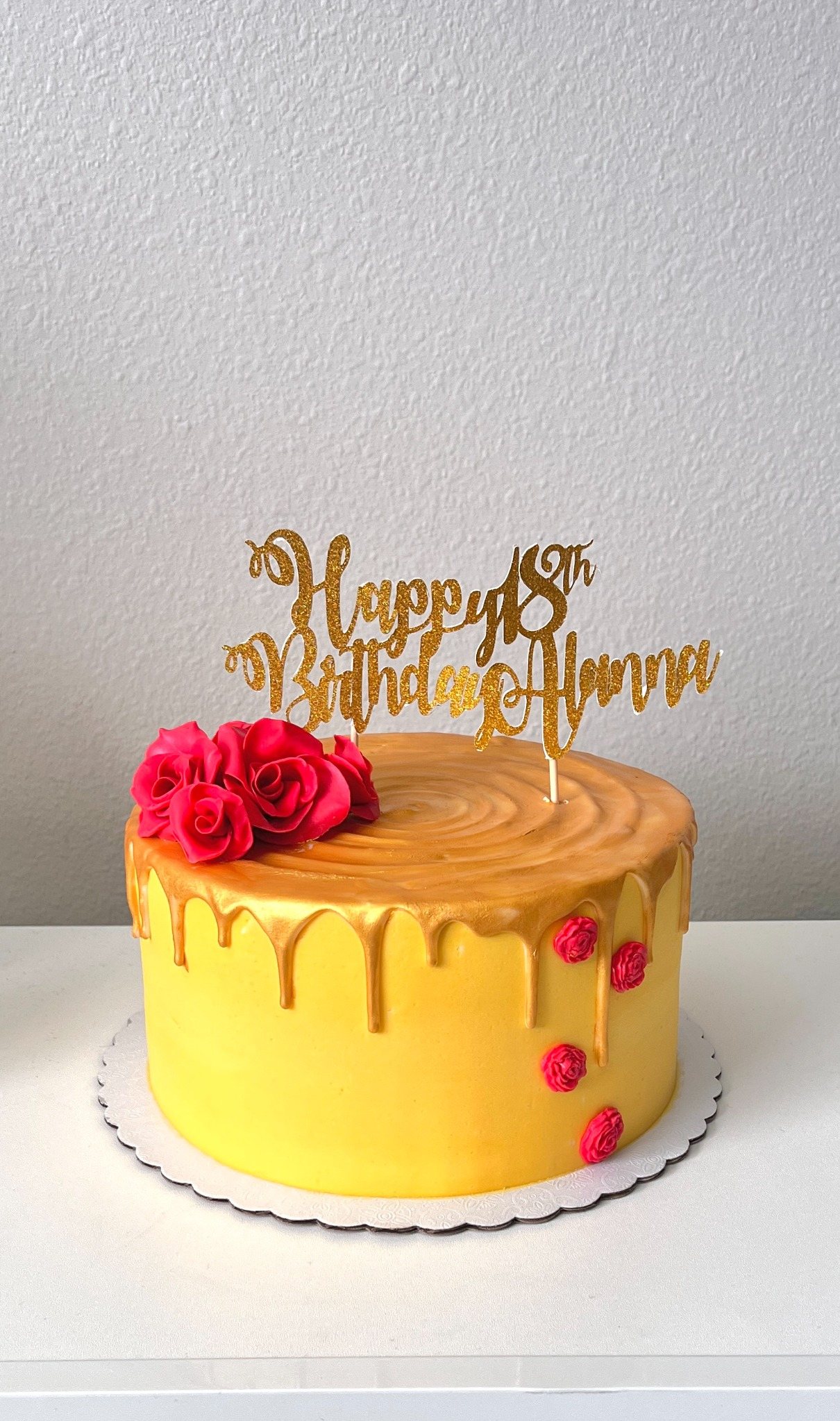 Yellow birthday cake with gold drip and red roses